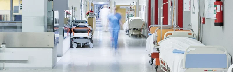 Flur im Krankenhaus mit unscharfem Arzt in Bewegung und Lift rot und Bett